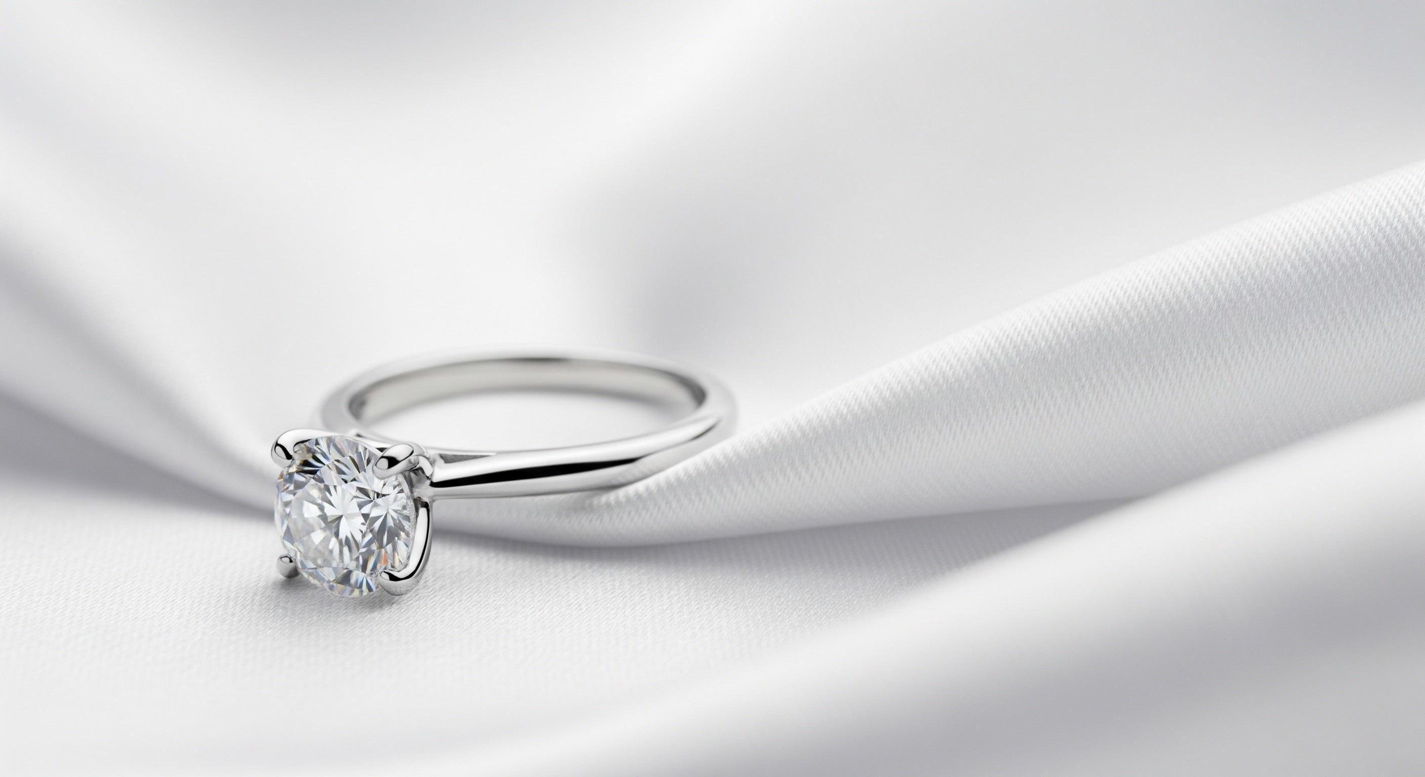 Silver ring with a diamond on a white fabric background
