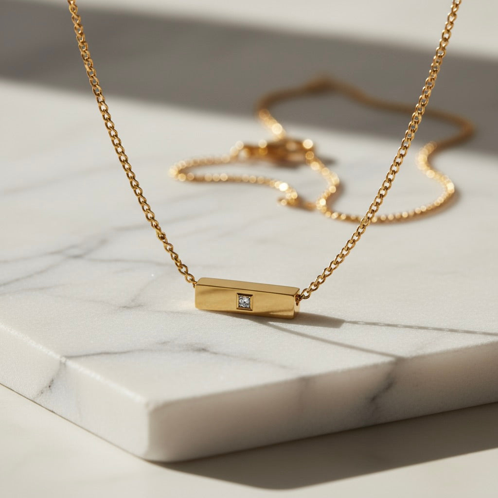 Gold necklace with a diamond pendant on a marble surface