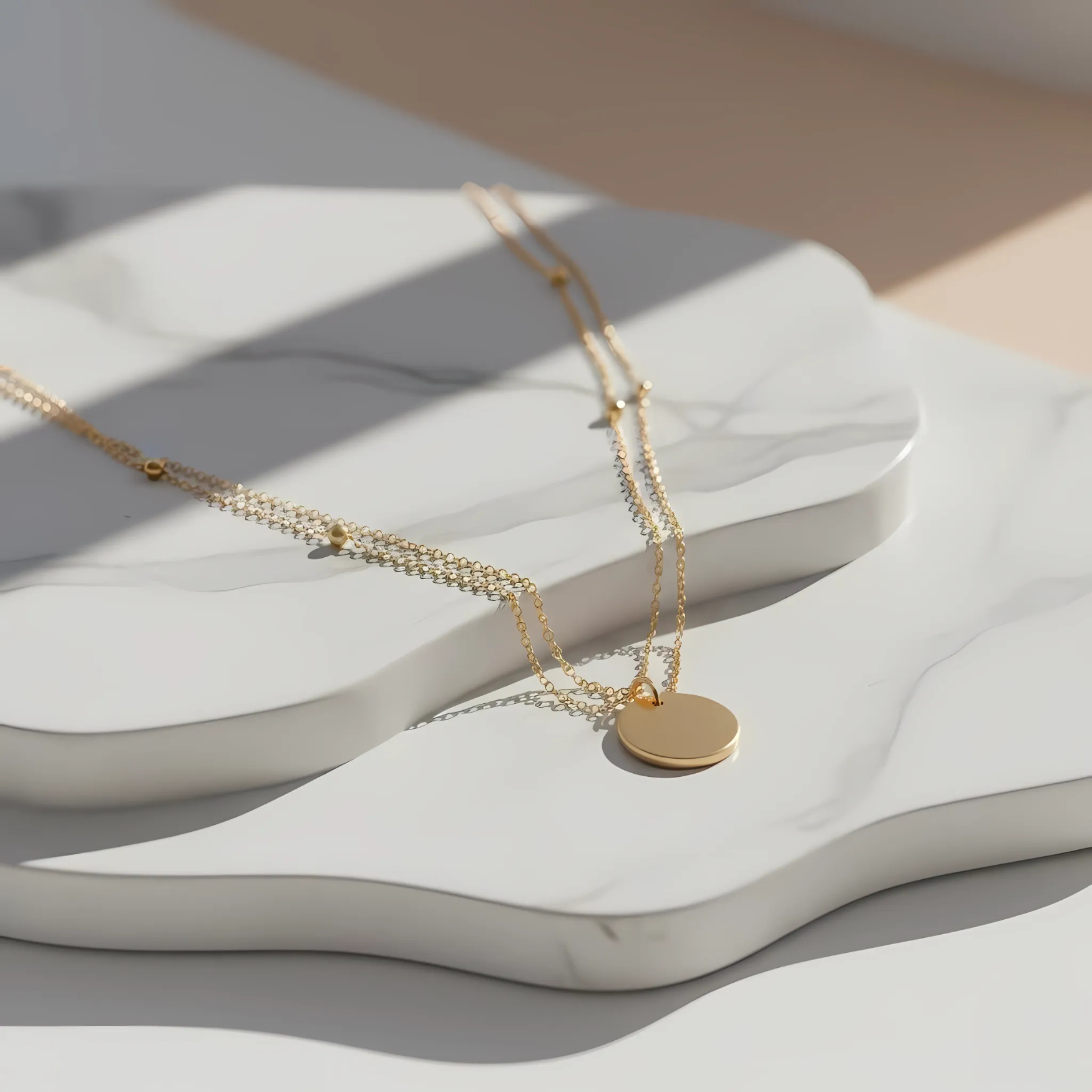 Gold necklace with a round pendant on a white, wavy surface